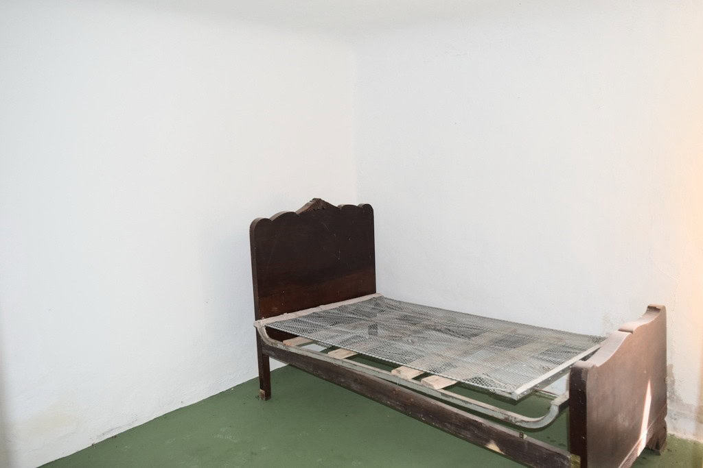 Rustic bedroom with vintage wooden bed frame in Benamaurel, Granada.