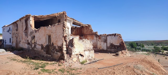 Ruin in Rejano, Granada with crumbling walls and exposed structure under a clear blue sky.