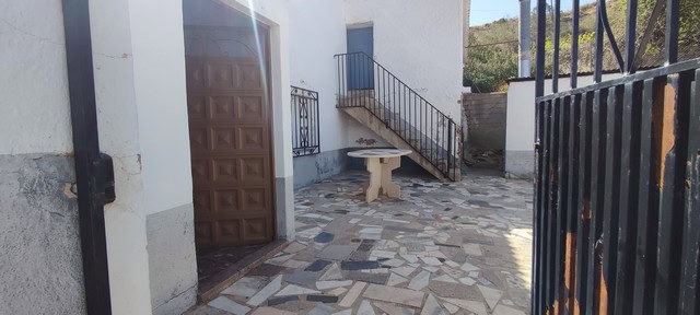 Cave house entrance with stone patio and outdoor seating in Caniles, Granada. Authentic rural proper.