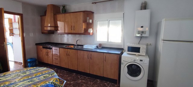 Interior of a traditional cave house in Caniles, Granada, featuring a compact kitchen and laundry ar.