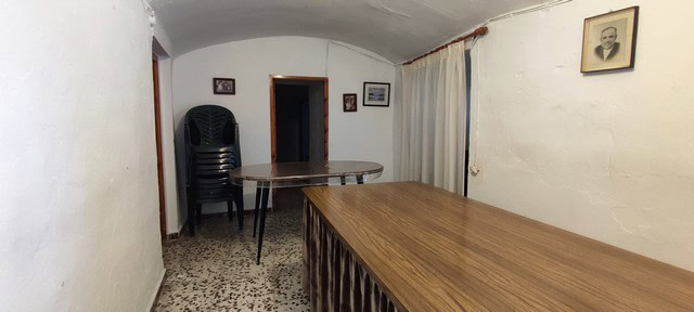 Interior of a rustic cave house with white walls, simple furniture, and cozy ambiance in Caniles, Gr.