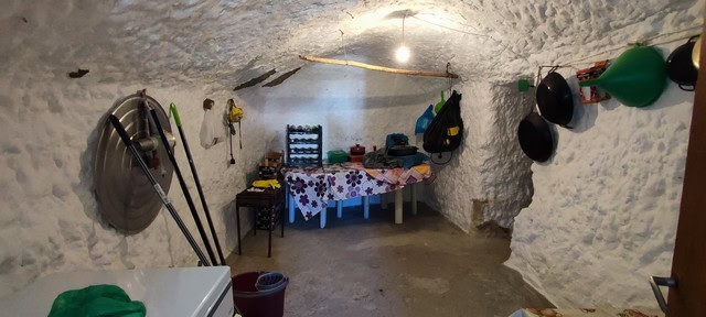 Cave house interior in Caniles, Granada, showcasing rustic stone walls and simple furnishings.