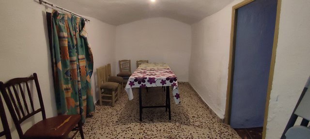 Cave house interior in Caniles, Granada, featuring simple furnishings and rustic charm.