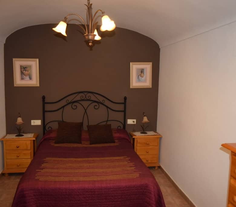Charming cave house bedroom in Gorafe, Granada, featuring rustic decor and comfortable bedding.