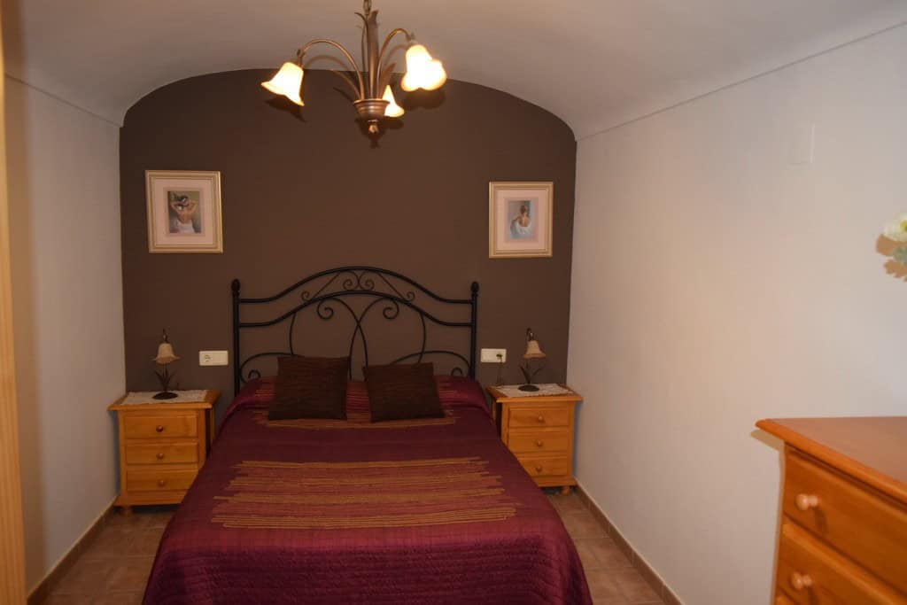 Charming cave house bedroom in Gorafe, Granada, featuring rustic decor and comfortable bedding.