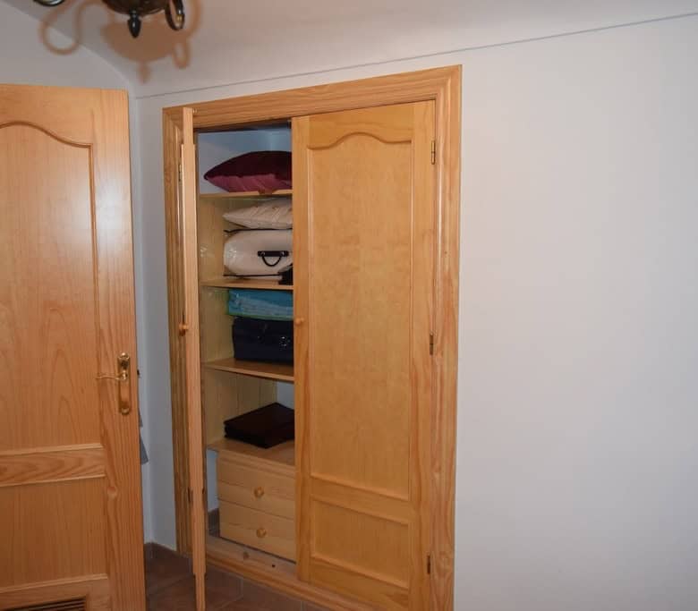 Unique cave house interior in Gorafe, Granada, with wooden closet and simple decor.