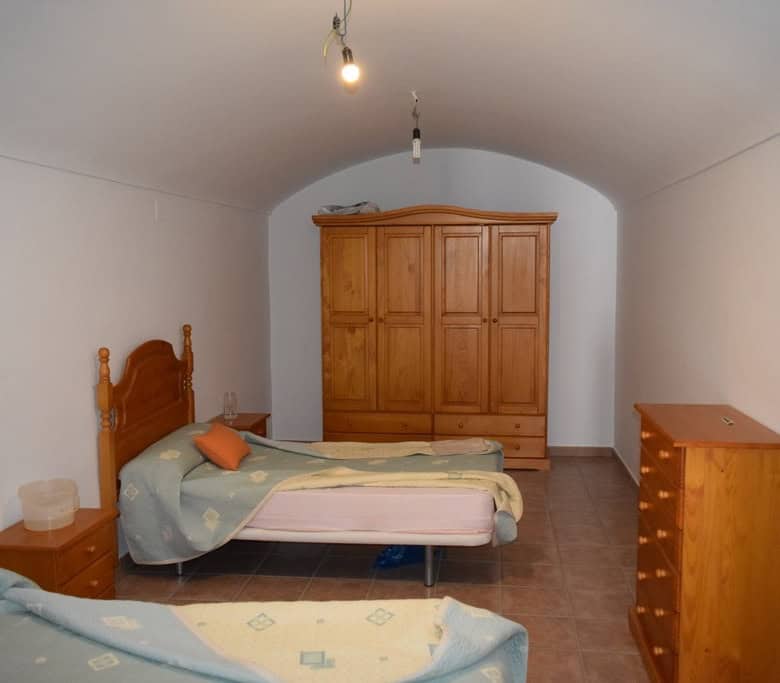 Charming interior of a cave house in Gorafe, Granada, featuring simple wooden furniture and cozy sle.