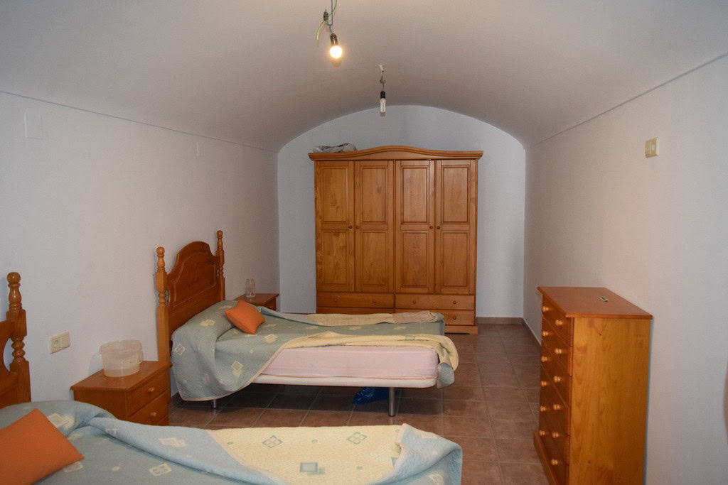 Charming interior of a cave house in Gorafe, Granada, featuring simple wooden furniture and cozy sle.