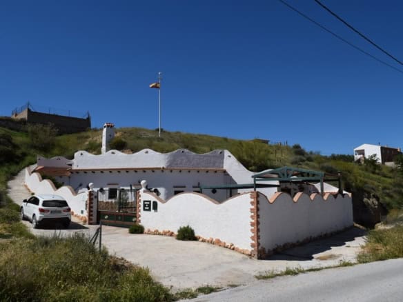 Cave house with white exterior walls and unique curved roof in Cortes de Baza, Granada.