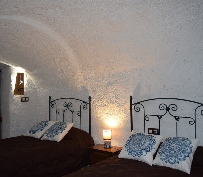Cave house interior with two beds and decorative pillows in Cortes de Baza, Granada. Unique undergro.