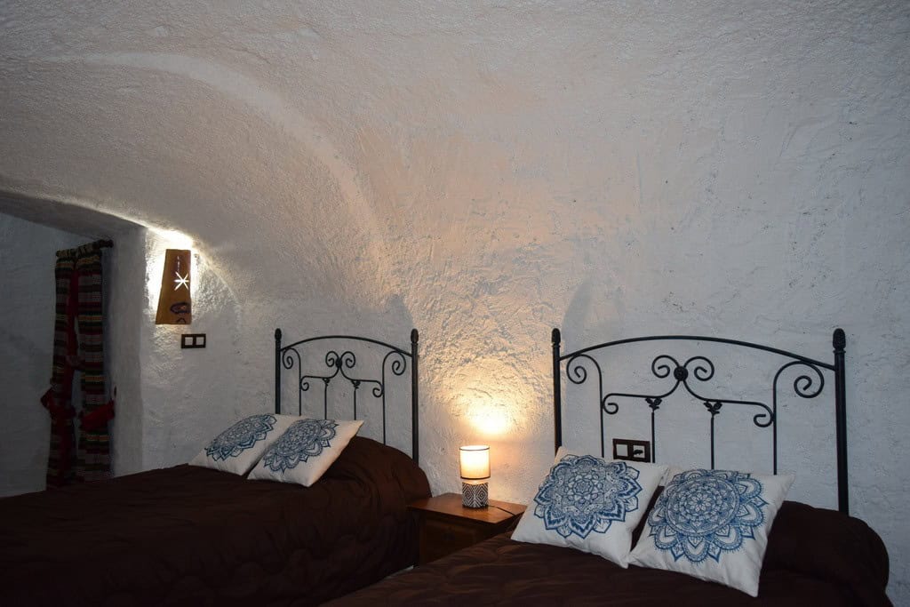Cave house interior with two beds and decorative pillows in Cortes de Baza, Granada. Unique undergro.