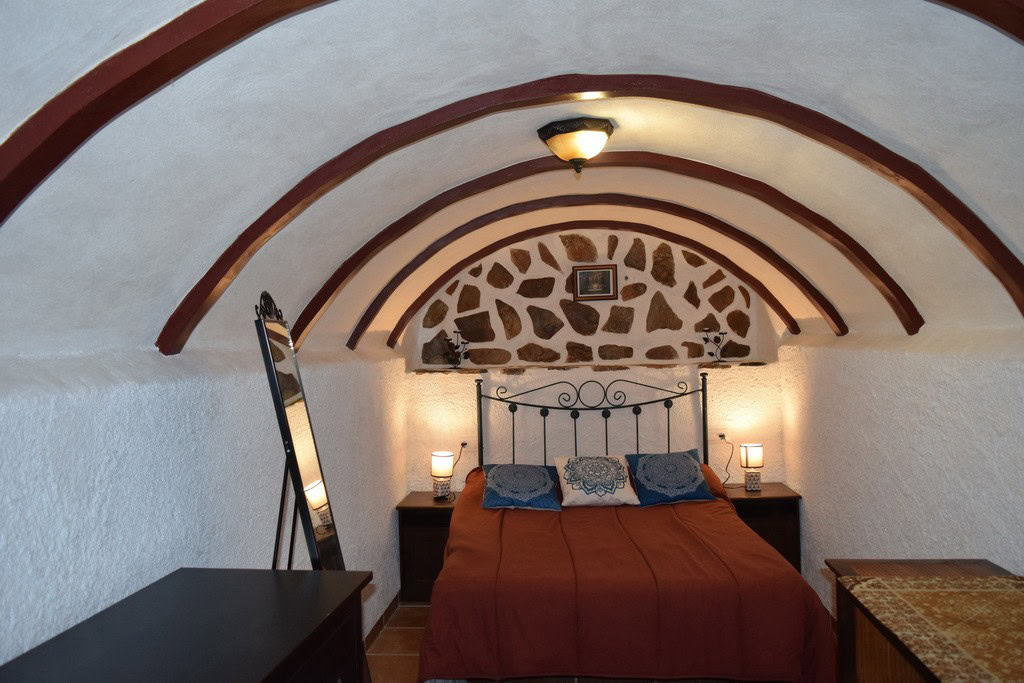 Charming cave house bedroom in Cortes de Baza, Granada with rustic stone walls and cozy interior des.