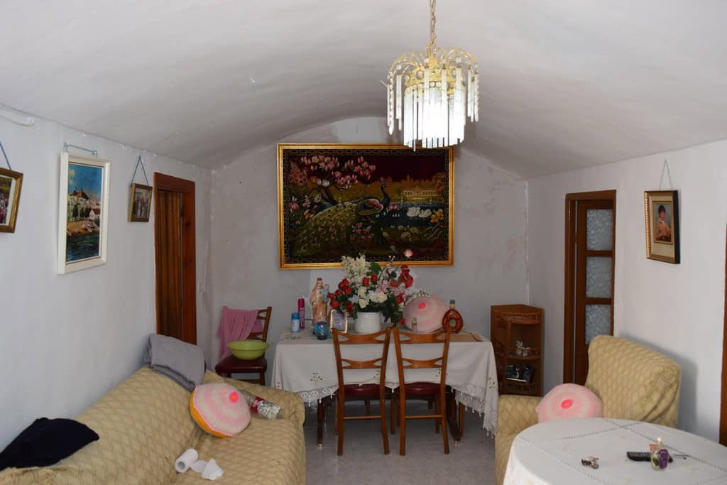 Interior view of a traditional cave house in Bacor, Granada, featuring cozy seating and decorative a.