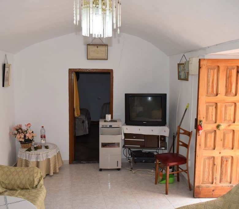 Charming cave house interior in Bacor, Granada, featuring rustic wooden door, vintage furniture, and.