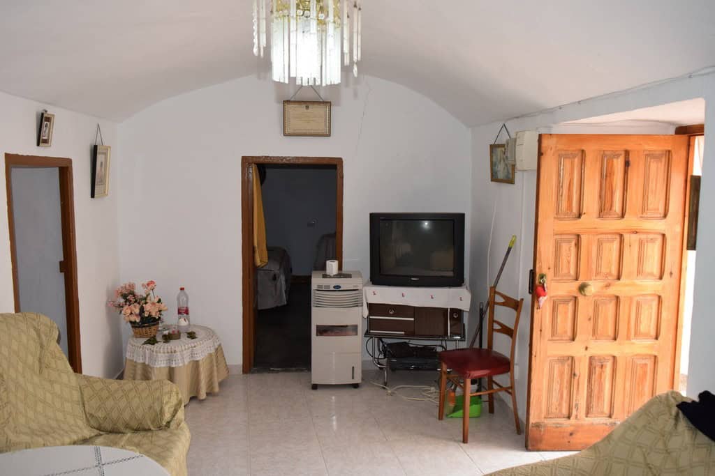 Charming cave house interior in Bacor, Granada, featuring rustic wooden door, vintage furniture, and.