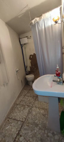 Interior view of a rustic village bathroom in Bayarque, Almeria, showing a simple toilet and sink wi.