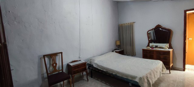 Interior view of a simple village property bedroom in Bayarque, Almeria, featuring basic furniture a.