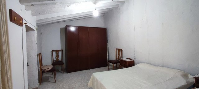 Interior view of a simple village house bedroom in Bayarque, Almeria, featuring basic furniture and.