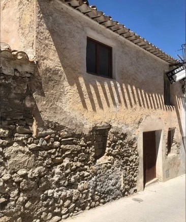 Traditional village house in Bayarque, Almeria, with rustic stone walls and a sunny facade.
