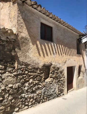 Traditional village house in Bayarque, Almeria, with rustic stone walls and a sunny facade.