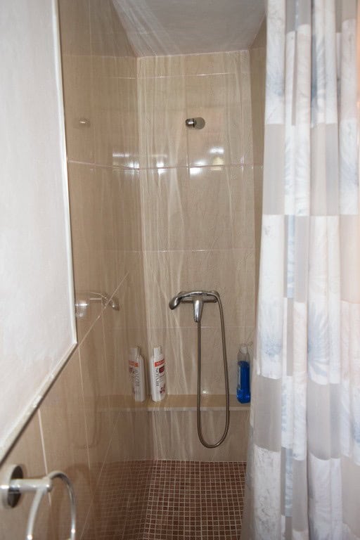 Cozy shower area in a cave house located in El Margen, Granada, featuring beige tiled walls and mode.