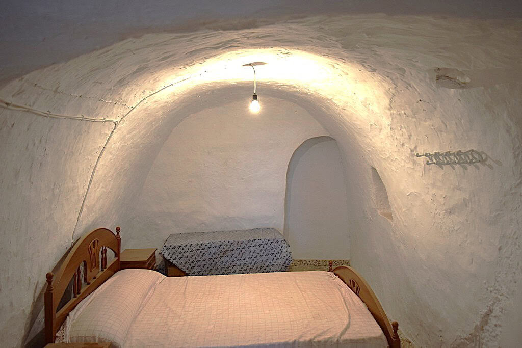 Cave house interior in El Margen, Granada with rustic stone walls and cozy bedroom. Unique undergrou.