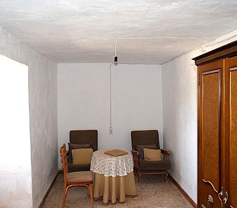 Interior view of a rustic cave house with vintage furniture in El Margen, Granada.