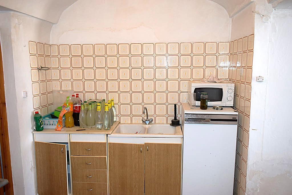 Charming cave house kitchen in El Margen, Granada, featuring basic appliances and rustic decor.