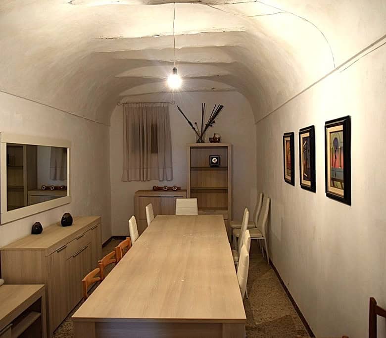 Cave house interior with a dining table, chairs, and cozy decor in El Margen, Granada.