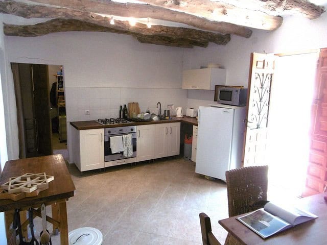 Charming rural kitchen in Hijate, Almeria with rustic wooden beams and modern appliances.