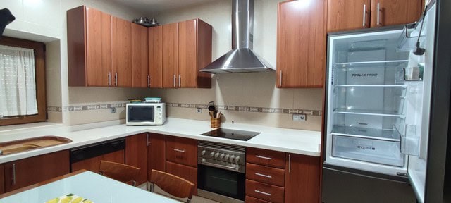 Modern kitchen with wooden cabinets and stainless steel appliances in Tijola, Almeria.