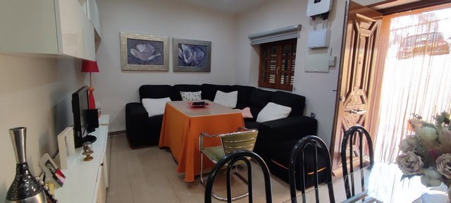 Cozy living room in a town house in Tijola, Almeria, featuring a black sofa, decorative artwork, and.