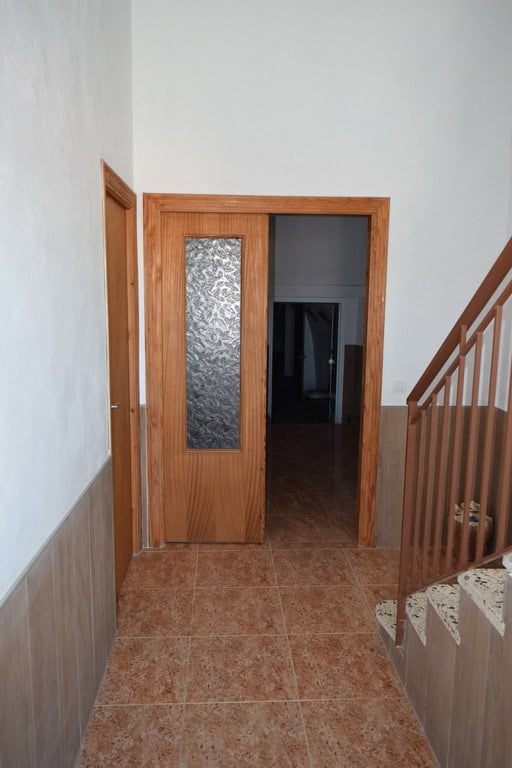 Charming cave house entrance in Castillejar, Granada with wooden door and staircase.