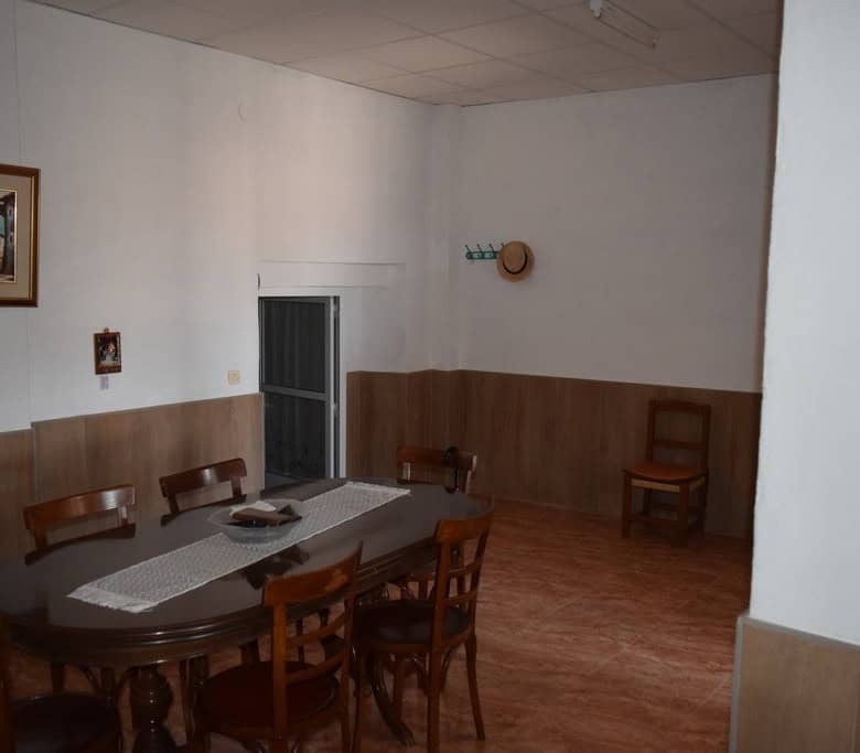 Charming interior of a cave house in Castillejar, Granada, featuring a dining area with wooden furni.