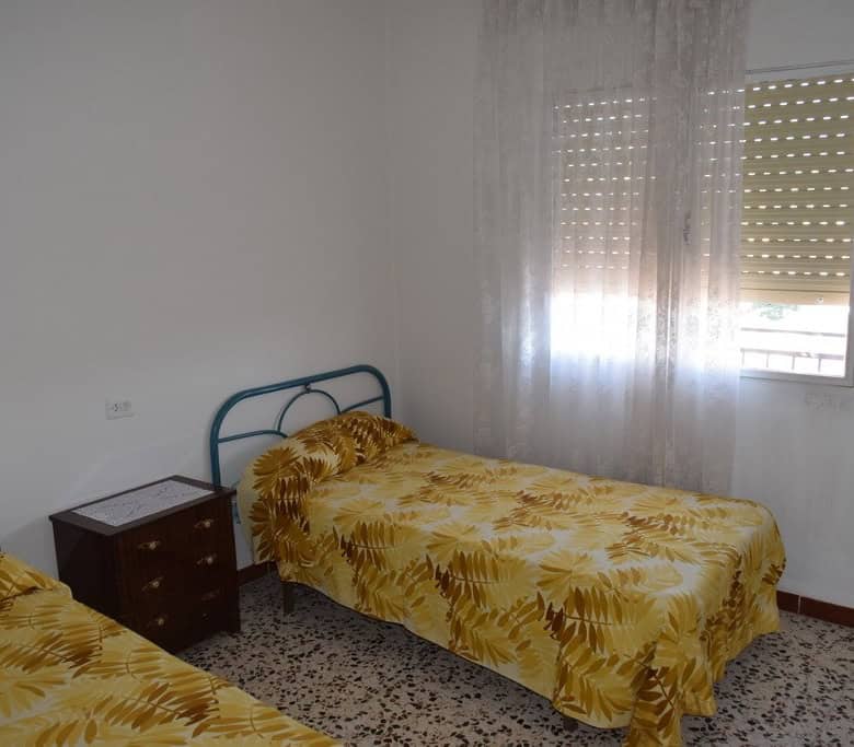 Cave house bedroom in Castillejar, Granada with two single beds and natural light.