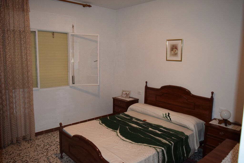 Interior view of a cozy cave house bedroom in Castillejar, Granada, featuring a wooden bed and simpl.
