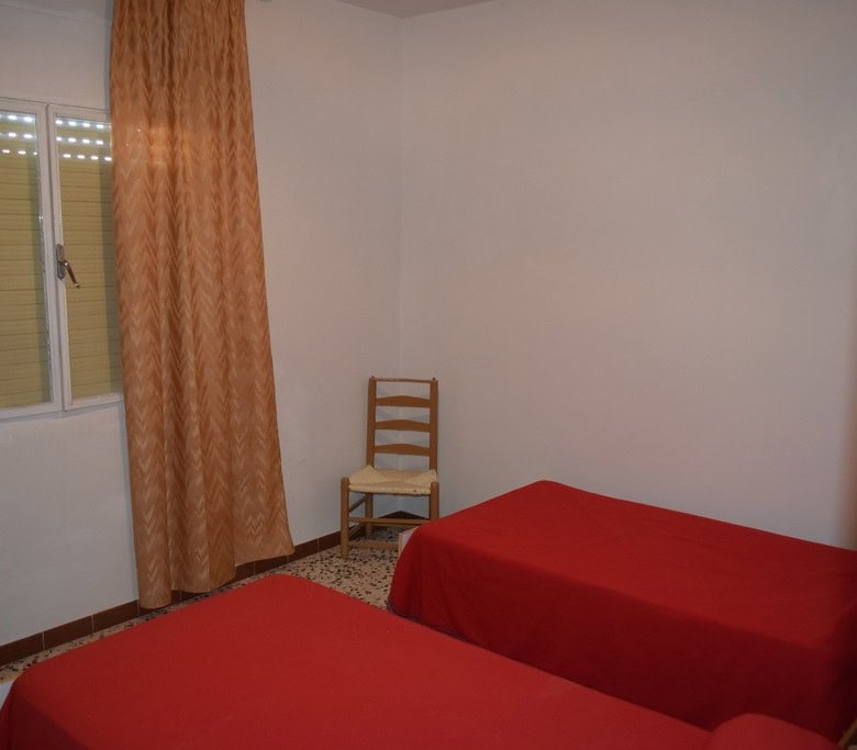 Charming cave house interior in Castillejar, Granada, featuring two single beds and simple furnishin.