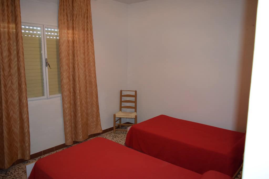 Charming cave house interior in Castillejar, Granada, featuring two single beds and simple furnishin.