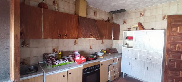 Kitchen of a town house in Tijola, Almeria, showing worn cabinets and basic appliances.