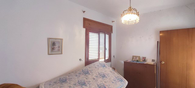 Bright bedroom with wooden window shutters and vintage furniture.