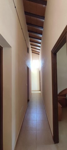 Interior corridor of a rural property in Sierro, Almeria, showing wooden ceiling beams and tiled flo.