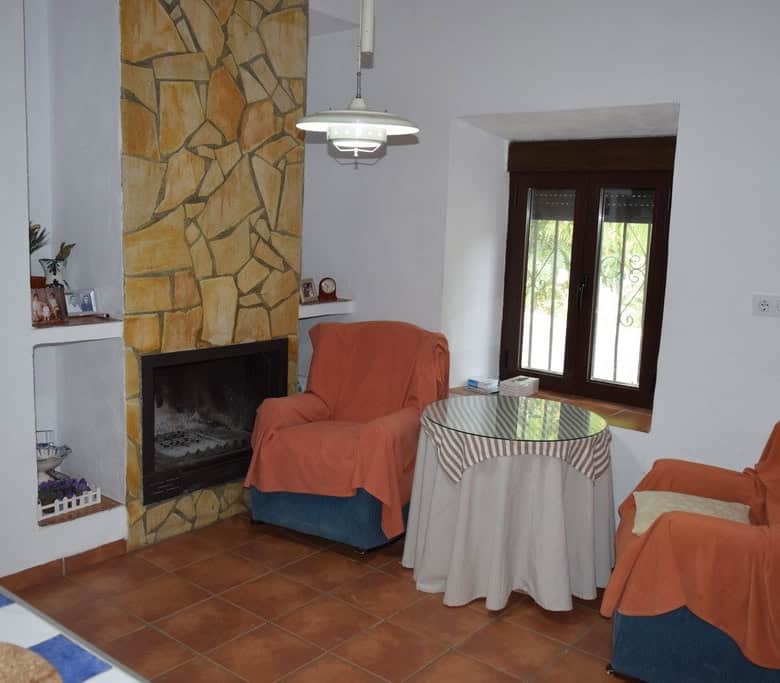 Charming village property interior with cozy seating area, fireplace, and natural light in Cortes de.
