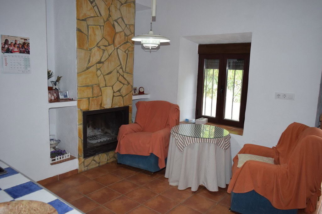 Charming village property interior with cozy seating area, fireplace, and natural light in Cortes de.