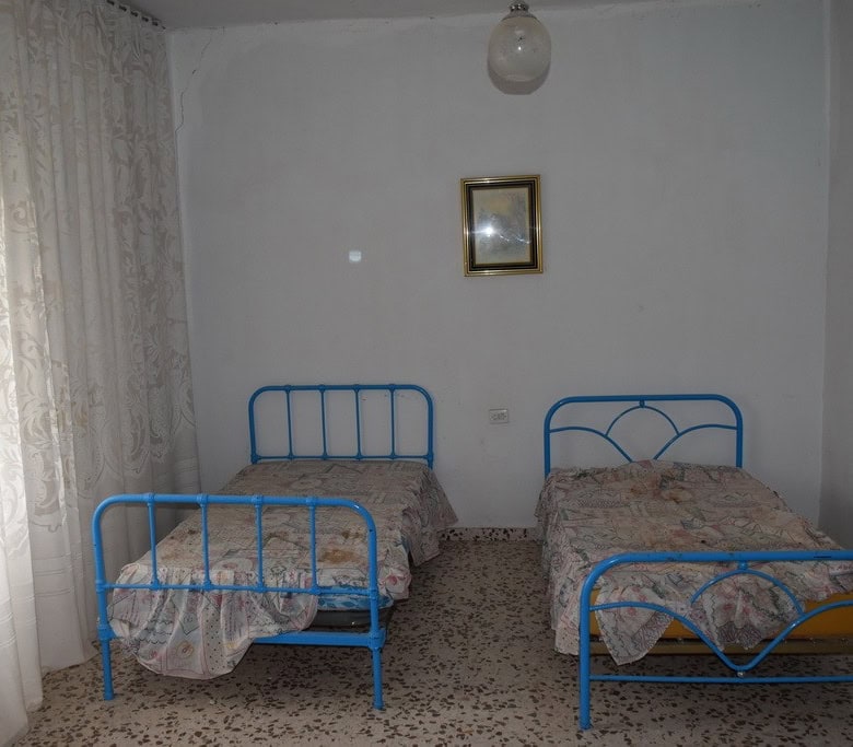 Charming bedroom with two blue metal beds in a rural village property in Cortes de Baza, Granada.