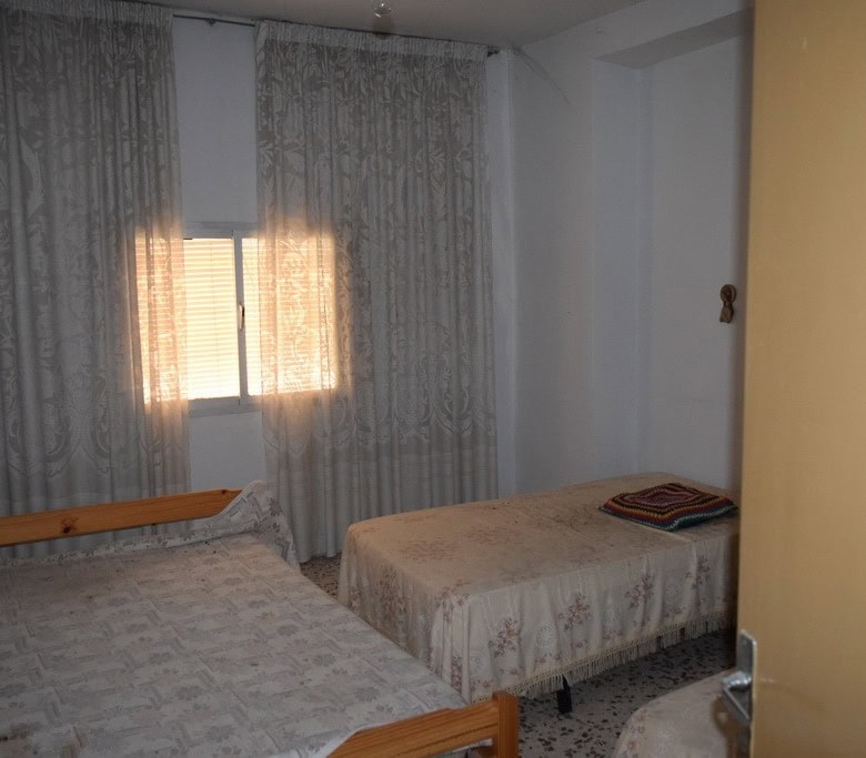 Bedroom with two single beds and lace curtains in Cortes de Baza village, Granada.