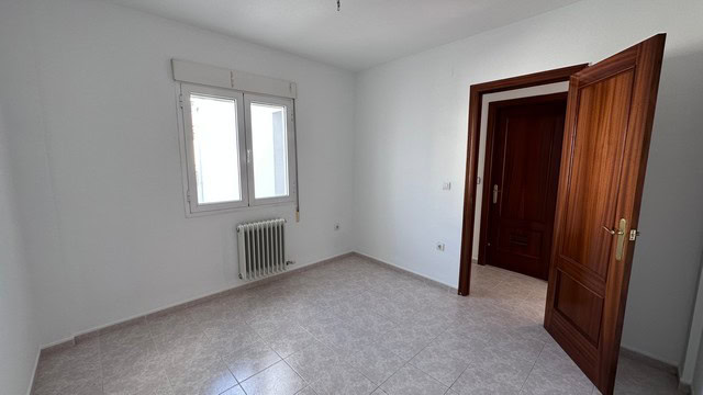 Bright interior of a town house in Caniles, Granada, featuring white walls, a window, and wooden doo.