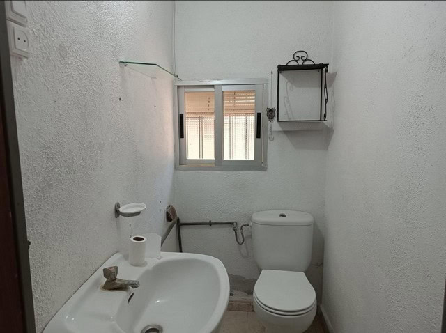 Interior of rural bathroom in Baza, Granada with basic fixtures and small window.