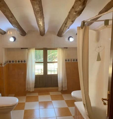 Cozy interior of a town house in Cullar, Granada, featuring rustic wooden beams and a bright window.