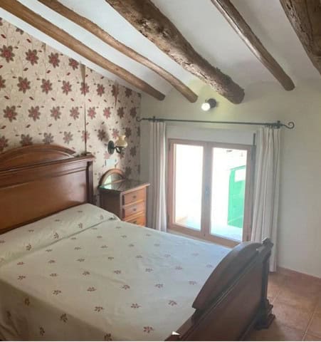 Charming bedroom in a traditional town house in Cullar, Granada, featuring rustic wooden beams and a.