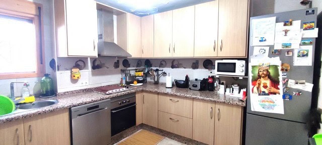 Kitchen with wooden cabinets, appliances, and a window in Albanchez village.